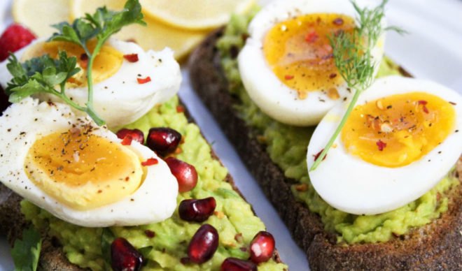 Close-up of avocado toast with hard-boiled eggs and pomegranate seeds