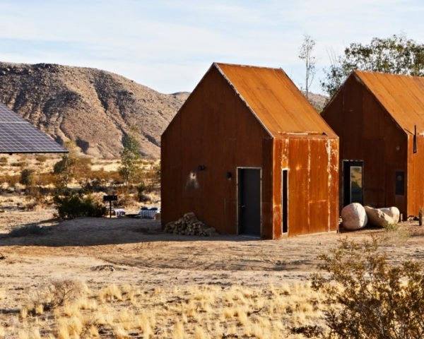 pair of rusted steel clad cabins in the desert