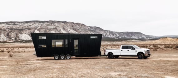Black RV being pulled by white truck