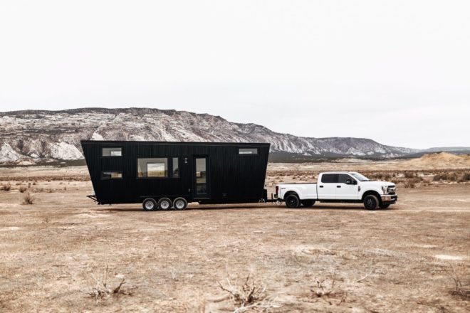 Black RV being pulled by white truck