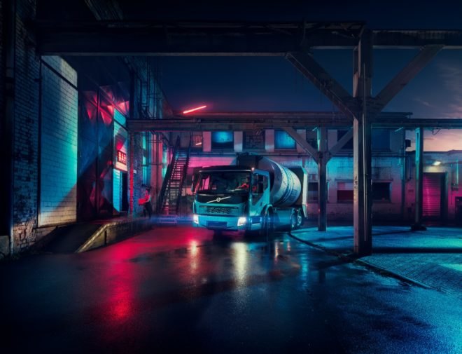 An electric Volvo truck parked in a colorful alley at night