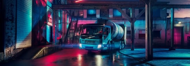 An electric Volvo truck parked in a colorful alley at night