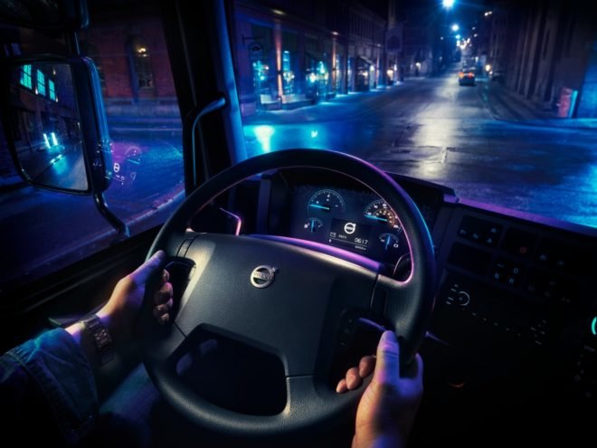 The steering wheel and driver's seat view from inside a Volvo electric truck at night