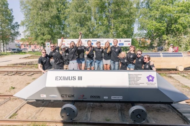 Biodegradable vehicle on tracks with students in background