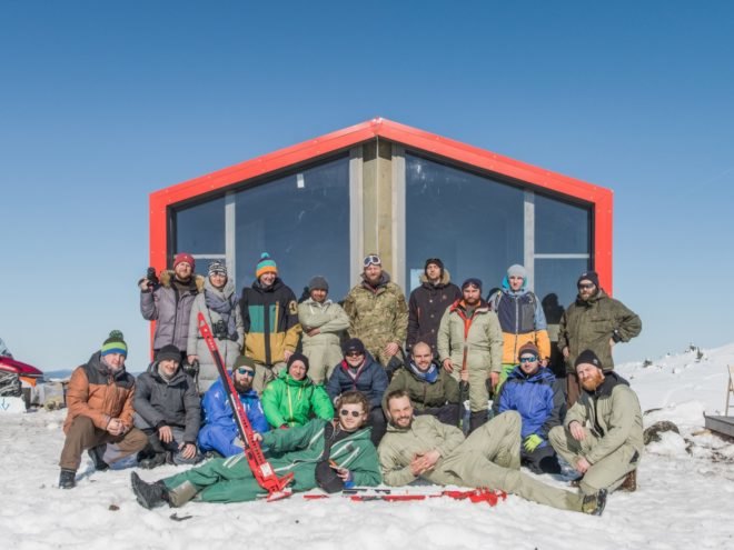 Skiiers and snowboarders gathered in front of the cabin