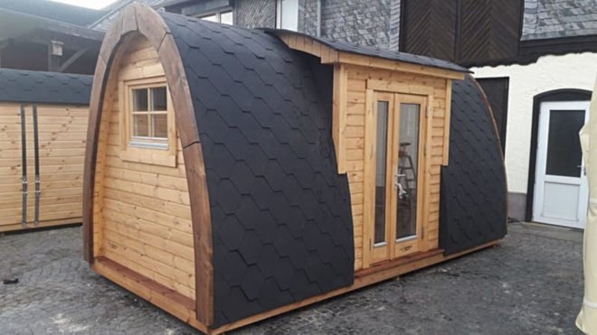 A curved cabin with black shingles