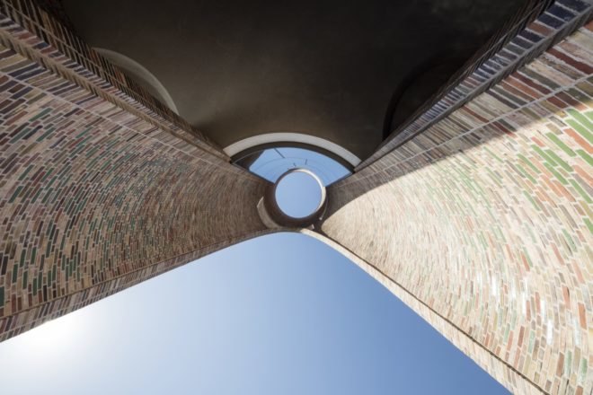 blue sky through circular opening in a building viewed from below