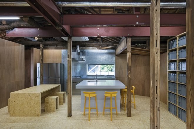kitchen with stainless steel refrigerators, a large island with yellow stools, and a timber dining table and chairs