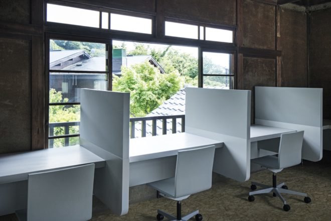 office area with three cubicles facing a large window