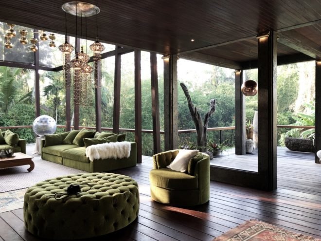 Moss-green furniture and hanging lamps in a room with glass walls
