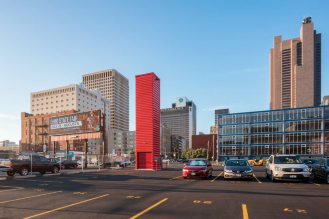 tall red shipping container tower in back of parking lot