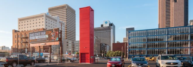tall red shipping container tower in back of parking lot