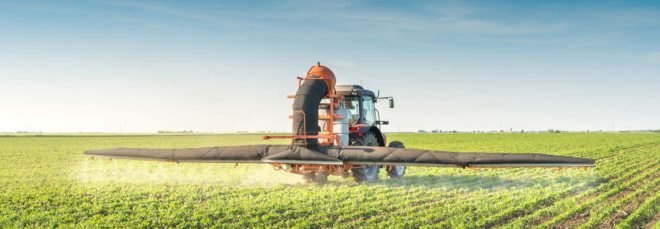 A tractor spraying pesticides on a field