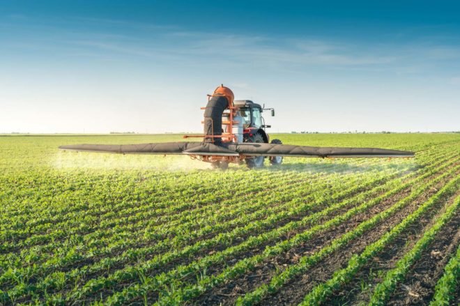 A tractor spraying pesticides on a field