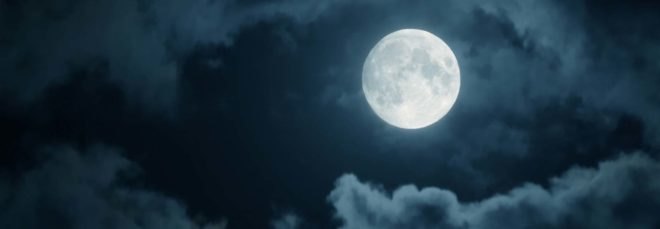 A full moon among nighttime clouds