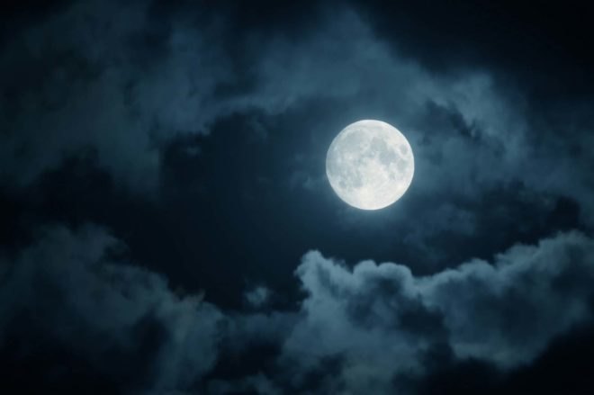 A full moon among nighttime clouds
