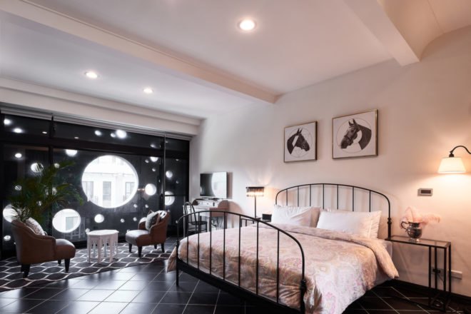 bedroom with large iron bed and black wall with large round windows