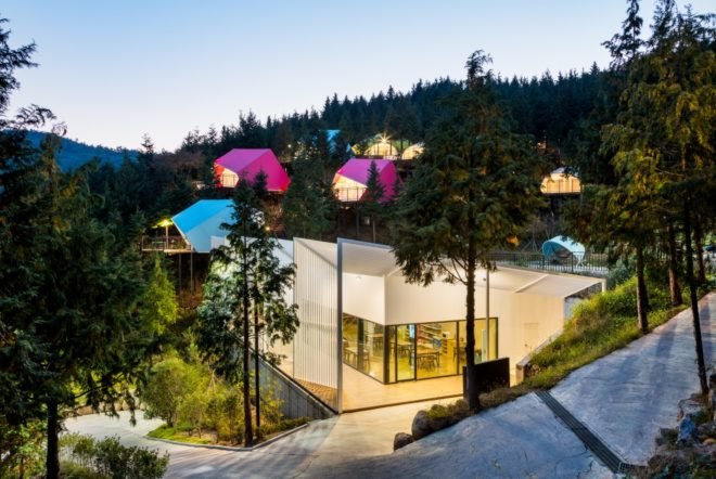 an illuminated white building with colorful pods in the background