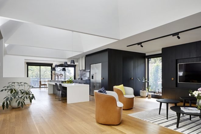 open plan kitchen, dining room and living room with white walls and ceilings, wood floors, and dark wood cabinetry in the kitchen and for the tv stand
