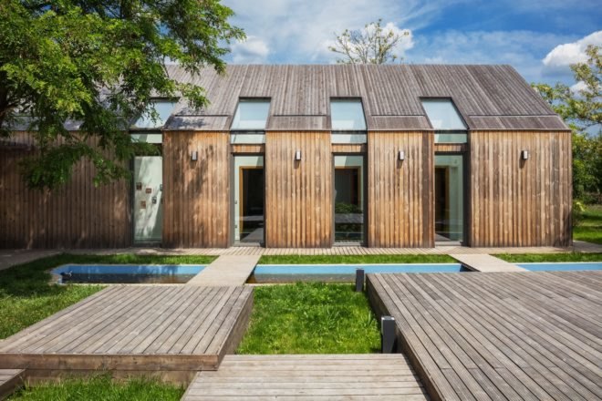 side of house with small wooden pathways, grassy areas and a rectangular pond