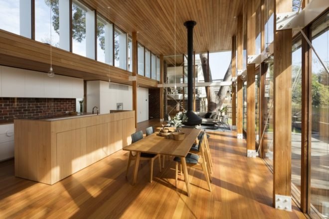 Open-plan kitchen and dining area with wood ceilings and floors, wood dining table, and white kitchen cabinets