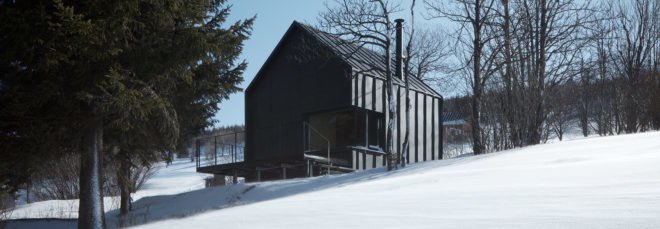 Black metal and wood cabin on snowy hill