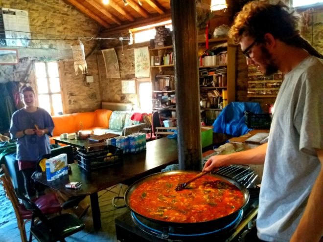 a man cooking a large pot of paella