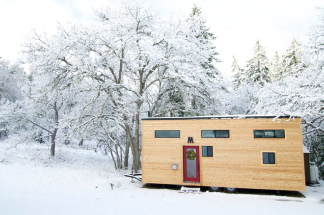 wooden tiny home with windows in snowy landscape