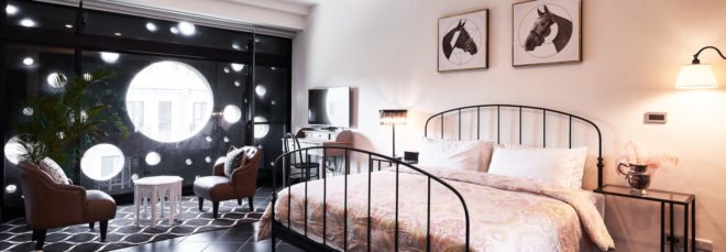 bedroom with large iron bed and black wall with large round windows