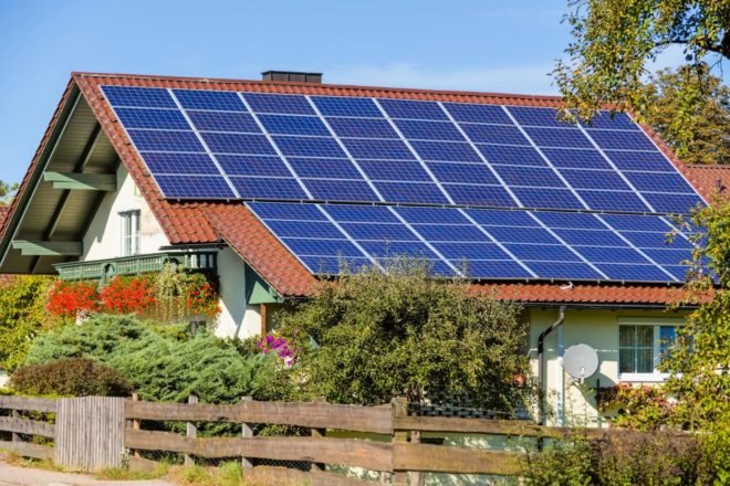 Solar panels on the roof of a home surrounded by plants