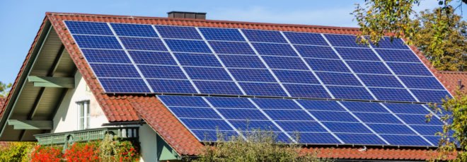 Solar panels on the roof of a home surrounded by plants