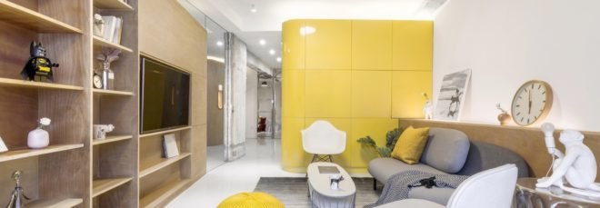 living room with timber entertainment center, gray couch, large yellow cube in background