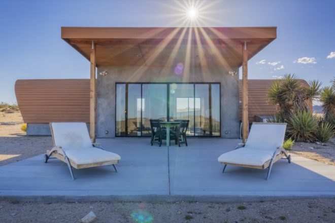 back patio with table and chairs as well as two white lounge chairs