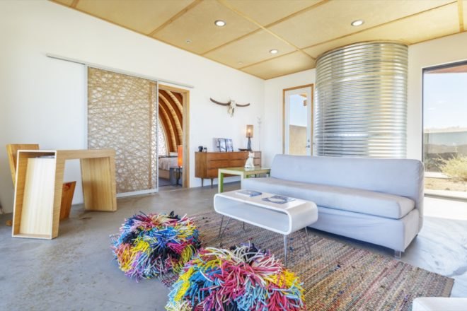 living room with light gray couch, white coffee table, and two colorful sitting poofs