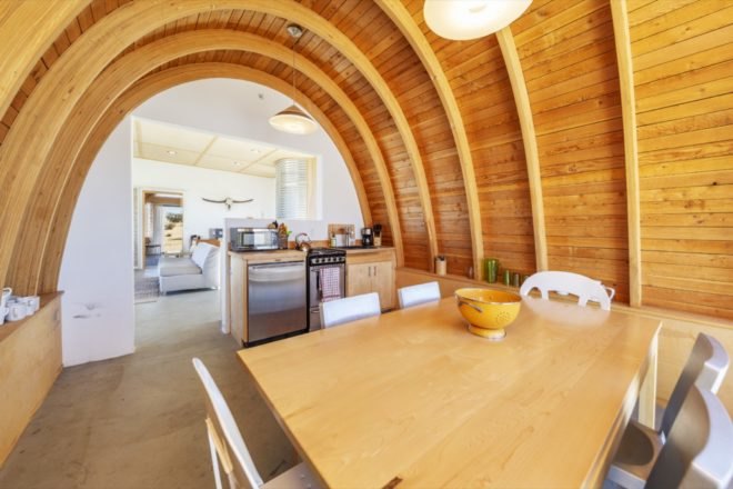 kitchen and dining space with wood table, wood cabinets, and a rounded wood ceiling