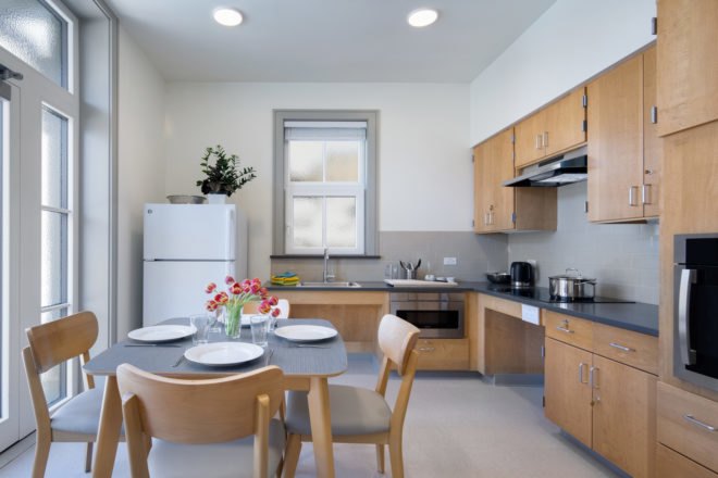 Modern kitchen with light wood cabinetry and a dining table with four chairs