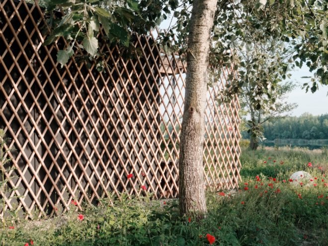 close up of dark exterior of cabin with light timber lattice over the dark facade