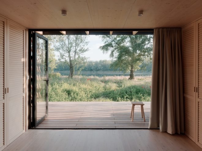 view of the lake from inside the home with doors opened to outside terrace