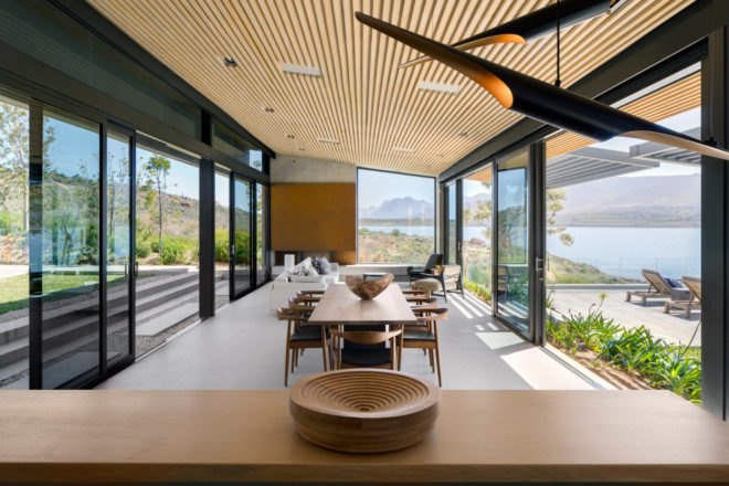 Dining area with long wooden table, wide windows, and chairs