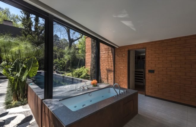 tub near large windows with views of pond and courtyard