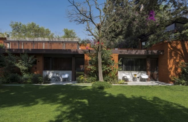 side view of the home with white chairs and tables near grassy yard and trees