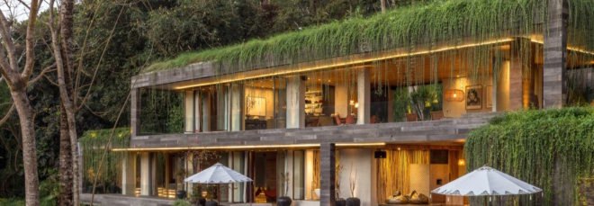 Home with green roof that has vegetation draping over and in front of the second floor balconies