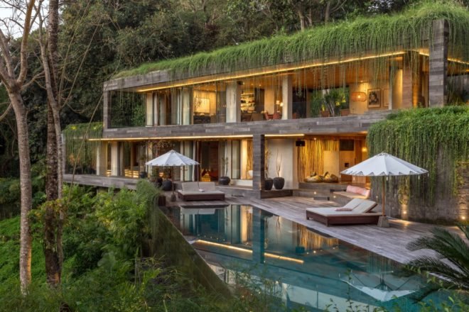 Large home with pool in front and lush, cascading green roofs