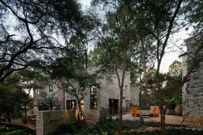 Stone home with outdoor patio surrounded by forest