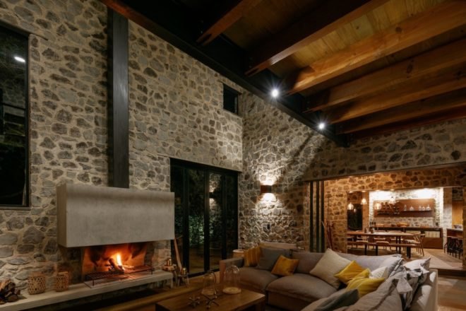 living room with open hearth fireplace, large gray couch and wood beam ceilings