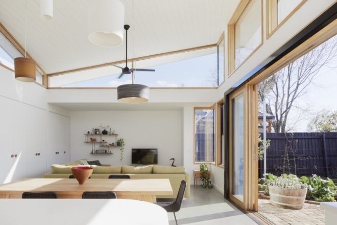 bright, open plan living area with large windows, light wood dining table, light colored couch and high ceilings