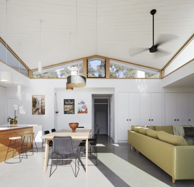 living room with high ceilings, light couch, wood dining table, and wall of white storage space