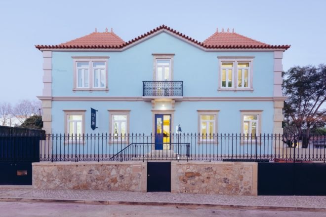 Pale blue hostel with open front door to bright yellow room