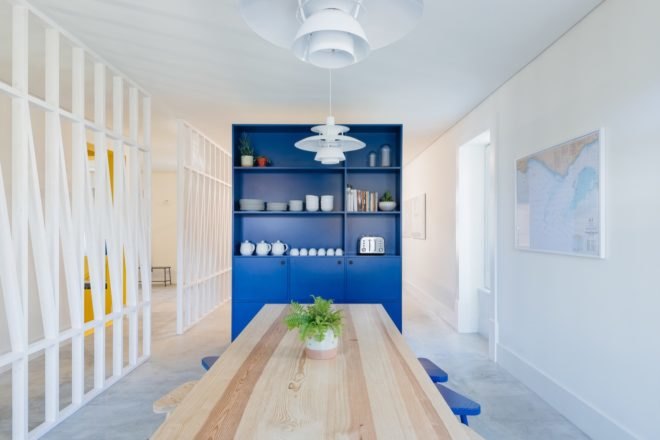 dining room with long light timber table and a tall blue shelving unit