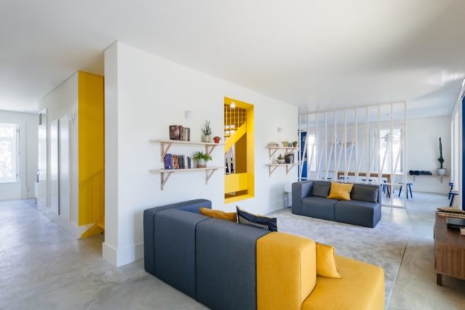Lounge area with gray and yellow couches and books on wall shelves